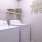 a white laundry room with a basket on top of a white washing machine
