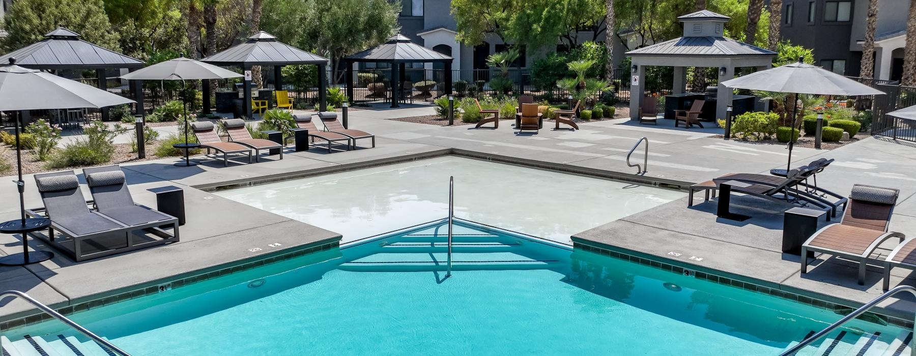 a pool with lounge chairs and umbrellas by it